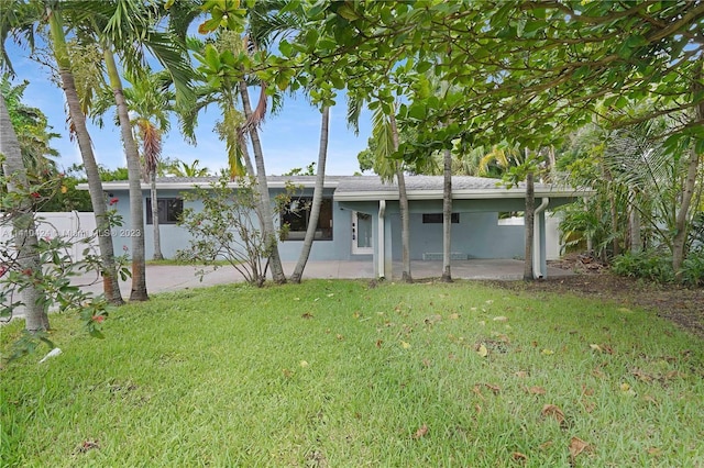 view of front of house with a patio area, stucco siding, a front lawn, and fence