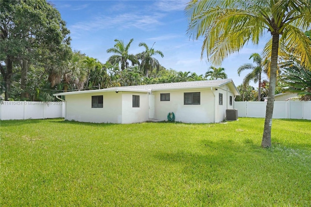 rear view of house with a yard, central AC, a fenced backyard, and stucco siding