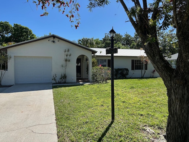 ranch-style home featuring a front yard, driveway, stucco siding, a garage, and metal roof