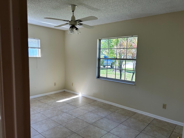 empty room with ceiling fan, light tile patterned floors, and a textured ceiling