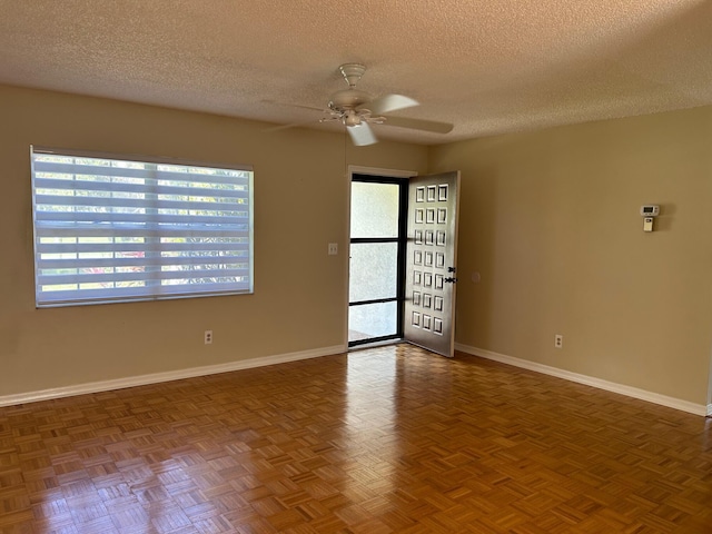 empty room featuring a ceiling fan, a healthy amount of sunlight, baseboards, and a textured ceiling