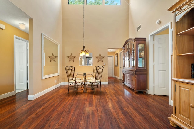 dining space with dark wood-type flooring, a high ceiling, baseboards, and visible vents