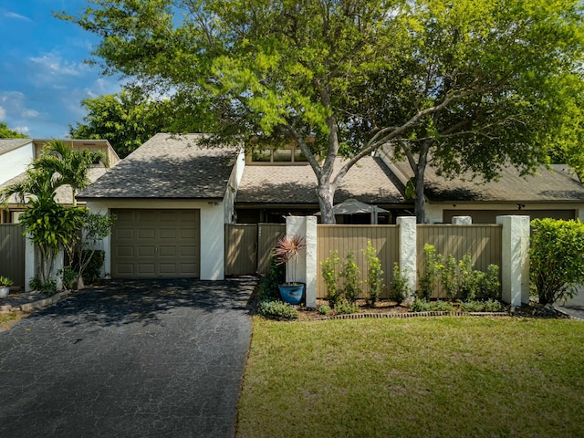 mid-century inspired home with fence, a front yard, roof with shingles, a garage, and driveway