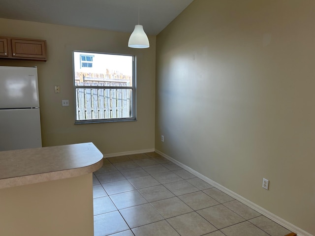 unfurnished dining area with light tile patterned floors and baseboards