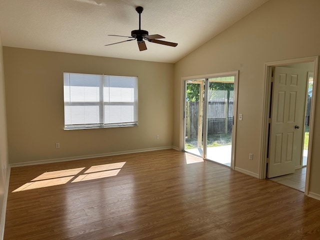 unfurnished room with a textured ceiling, a ceiling fan, lofted ceiling, and wood finished floors