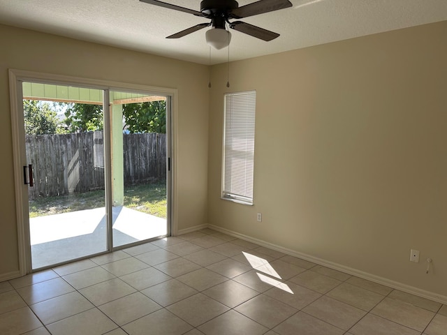 unfurnished room with light tile patterned flooring, a ceiling fan, baseboards, and a textured ceiling