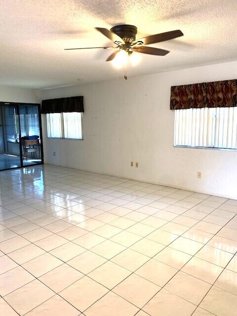 unfurnished room featuring light tile patterned floors, a textured ceiling, and a ceiling fan