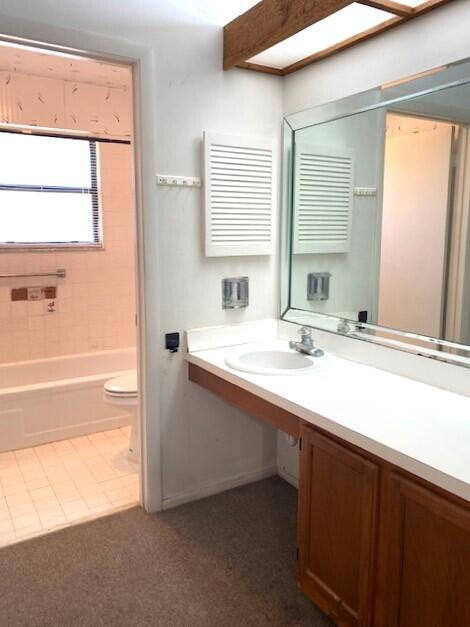 full bathroom featuring toilet, a tub to relax in, a skylight, a shower, and vanity