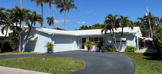 ranch-style house featuring a front lawn, a garage, driveway, and stucco siding