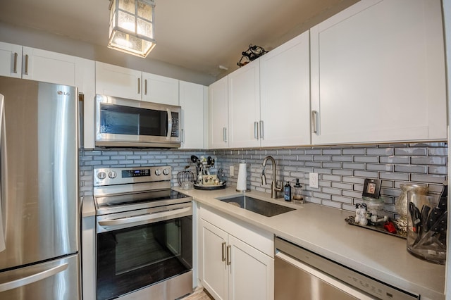 kitchen with a sink, decorative backsplash, light countertops, white cabinets, and appliances with stainless steel finishes