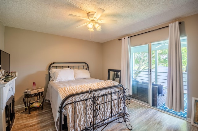 bedroom featuring a ceiling fan, a textured ceiling, wood finished floors, baseboards, and access to exterior