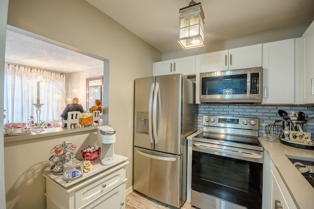 kitchen with stainless steel appliances, white cabinetry, backsplash, and light countertops