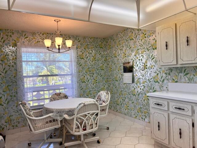 dining area featuring baseboards, a notable chandelier, and wallpapered walls