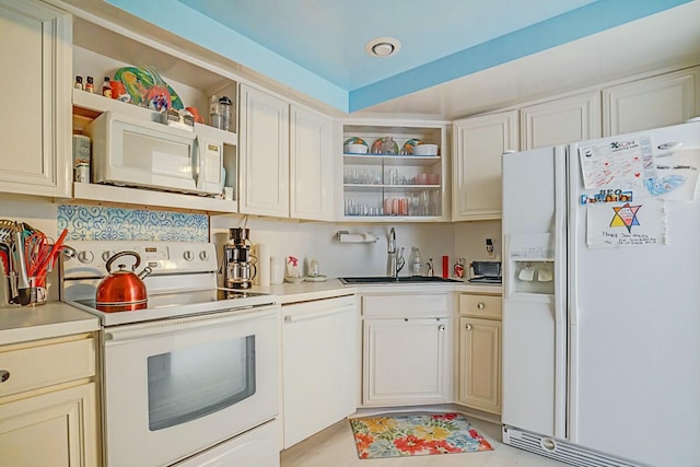 kitchen with open shelves, white appliances, cream cabinetry, and a sink