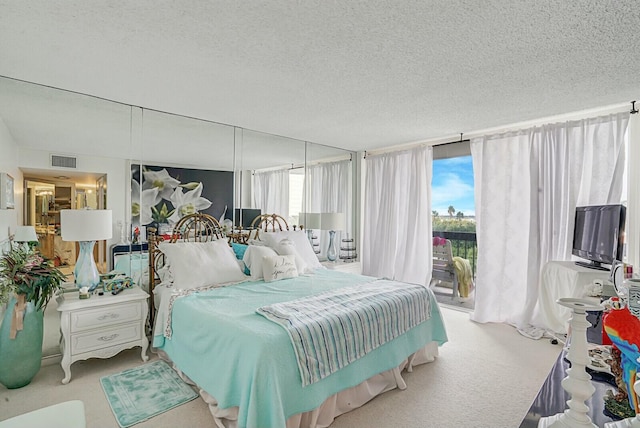 bedroom featuring access to outside, carpet flooring, visible vents, and a textured ceiling