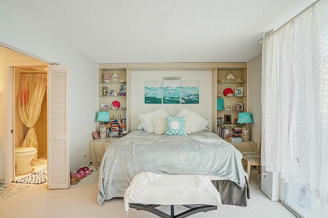 bedroom featuring ensuite bath, a textured ceiling, and carpet floors