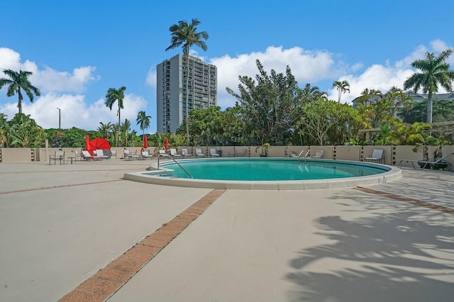 community pool with a patio and fence