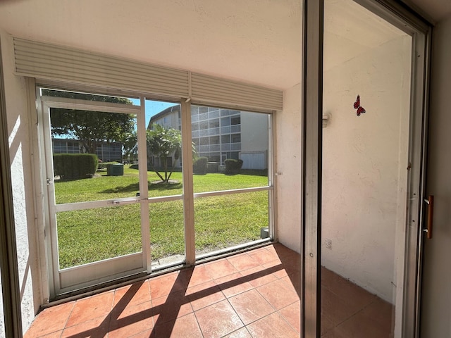 doorway to outside featuring tile patterned flooring and a textured wall