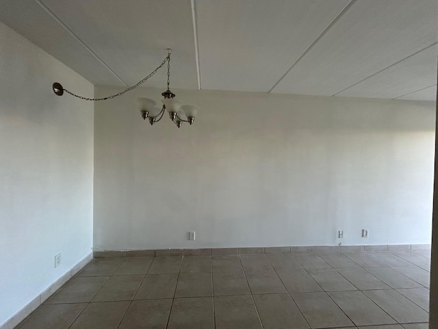 unfurnished dining area featuring light tile patterned floors, baseboards, and an inviting chandelier