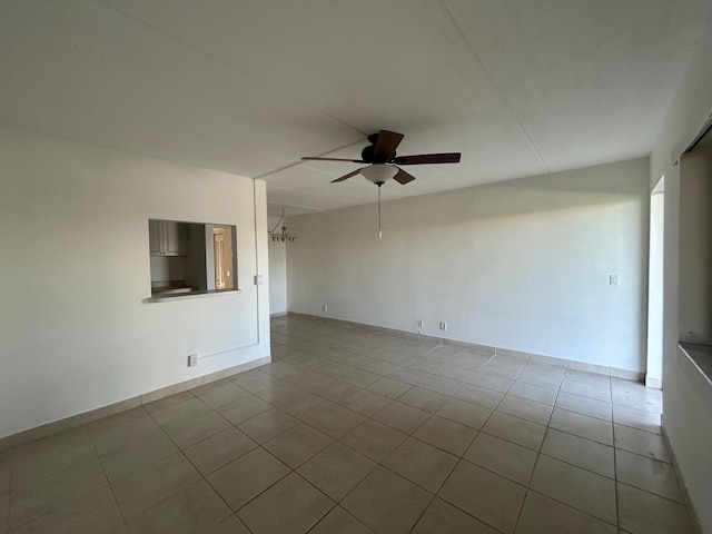 tiled empty room with a ceiling fan and baseboards