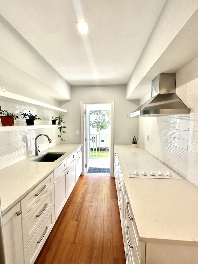 kitchen with dark wood finished floors, open shelves, a sink, wall chimney exhaust hood, and backsplash