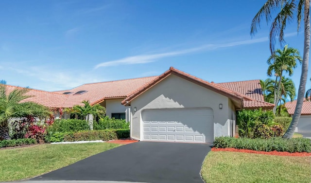 mediterranean / spanish-style home with stucco siding, a tiled roof, driveway, and a garage