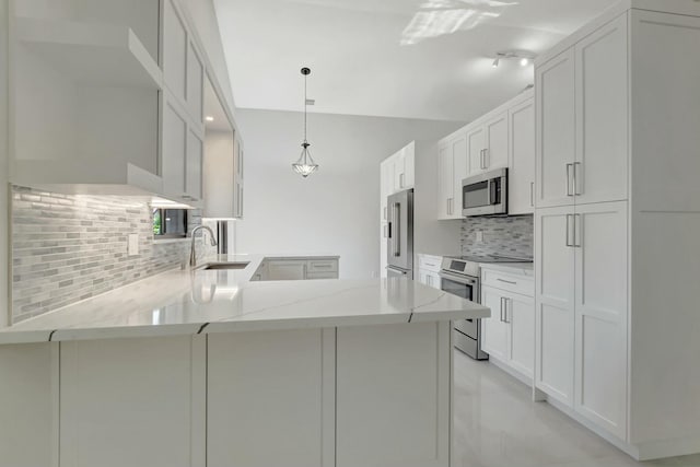kitchen with light stone counters, a peninsula, a sink, decorative backsplash, and stainless steel appliances