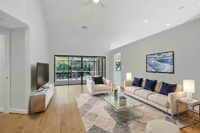 living area featuring visible vents, a high ceiling, ceiling fan, and light wood finished floors