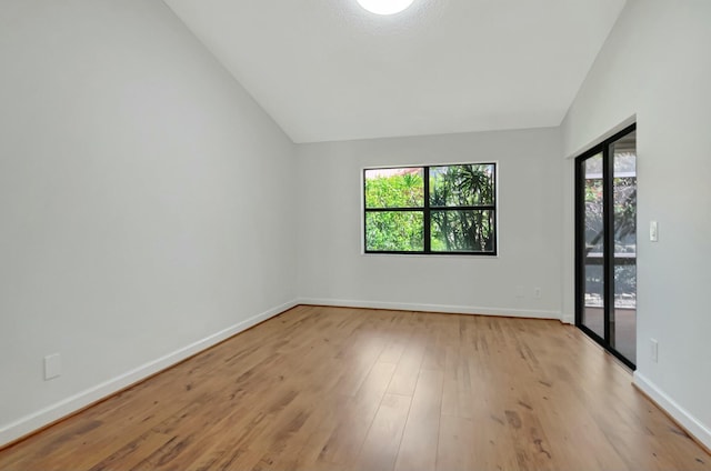 unfurnished room with baseboards, lofted ceiling, and wood finished floors
