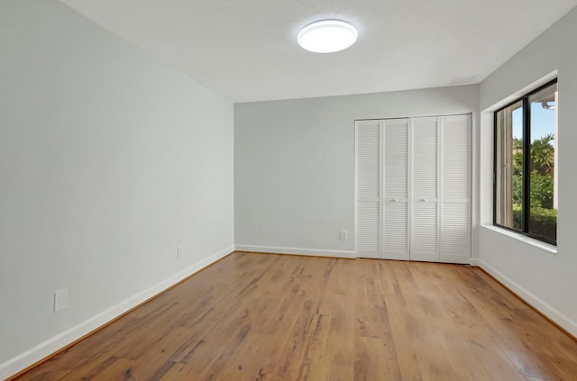 unfurnished bedroom featuring a closet, baseboards, and wood finished floors