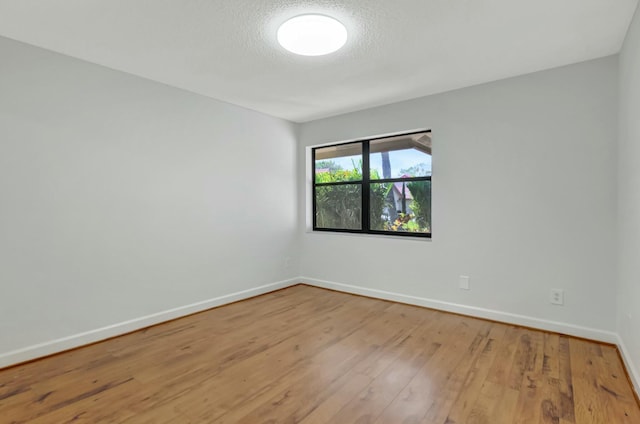 spare room featuring a textured ceiling, baseboards, and wood-type flooring
