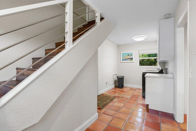 laundry area featuring tile patterned flooring, cabinet space, washer / clothes dryer, and baseboards