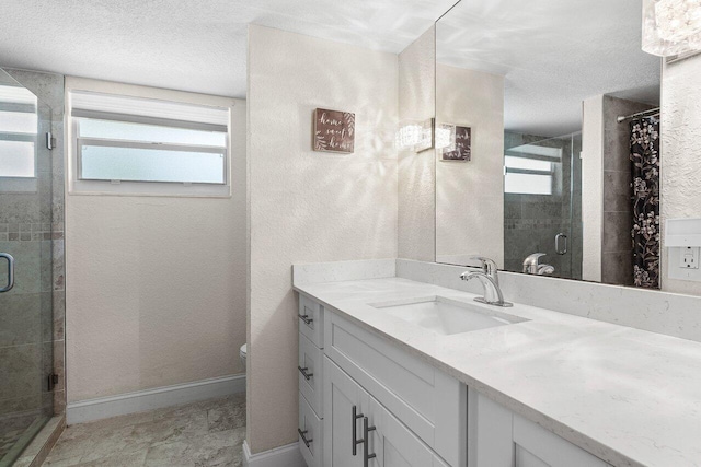 full bath featuring a shower stall, a textured ceiling, vanity, and baseboards