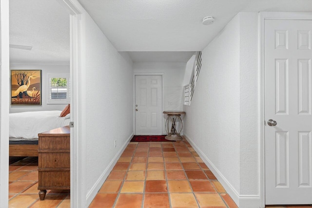 hallway with tile patterned floors, baseboards, and a textured ceiling