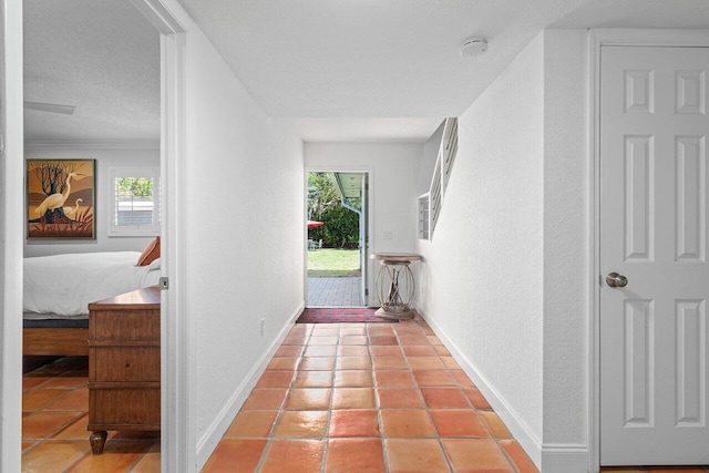 hallway featuring light tile patterned flooring, a textured ceiling, baseboards, and a textured wall