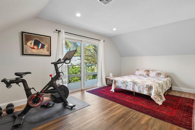 bedroom featuring a textured ceiling, wood finished floors, vaulted ceiling, and access to outside