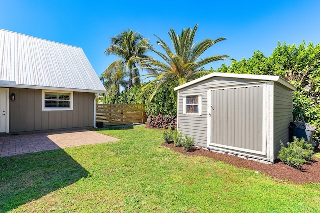 view of yard featuring a storage shed, an outbuilding, fence, and a patio