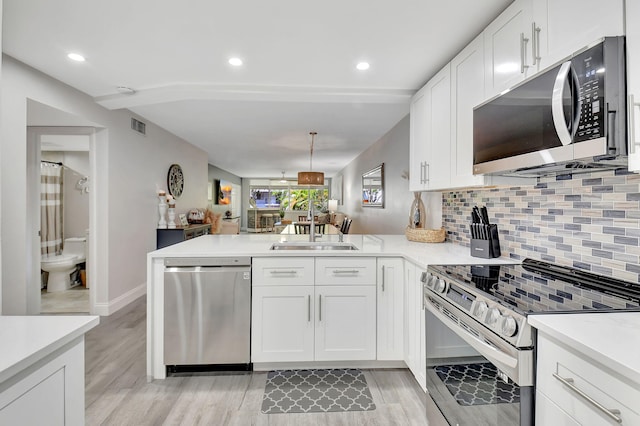 kitchen with a sink, stainless steel appliances, a peninsula, and light countertops