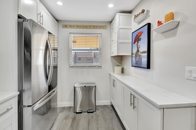 kitchen featuring light wood-type flooring, open shelves, freestanding refrigerator, white cabinets, and light countertops