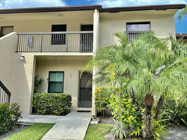 view of front of house with stucco siding and a balcony