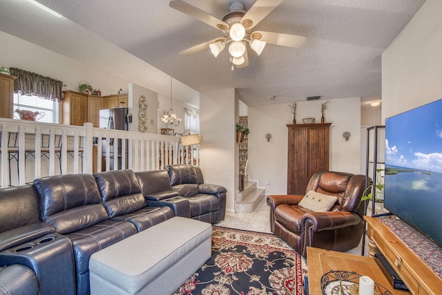 living area with light tile patterned floors, ceiling fan with notable chandelier, baseboards, and a textured ceiling