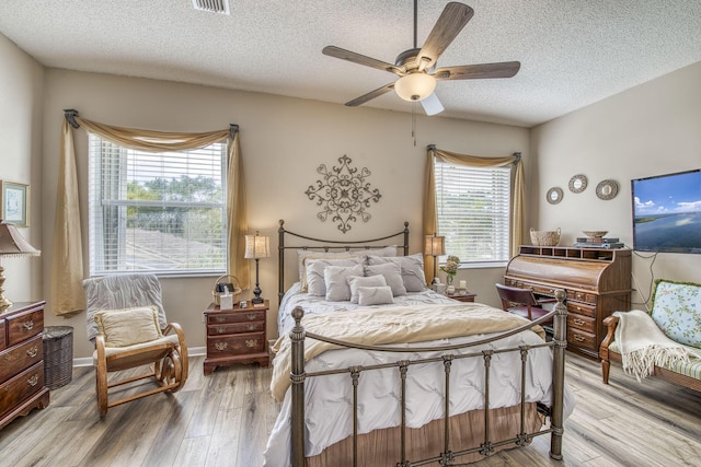 bedroom featuring light wood-style flooring, a ceiling fan, baseboards, and a textured ceiling