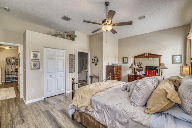 bedroom with visible vents, a textured ceiling, and wood finished floors