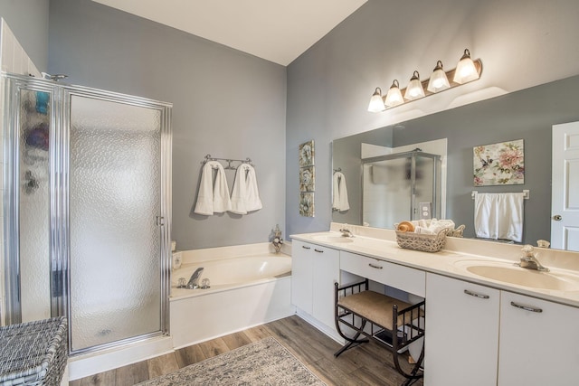 bathroom with a garden tub, a sink, wood finished floors, a shower stall, and double vanity