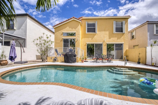 outdoor pool with a patio, fence, and grilling area