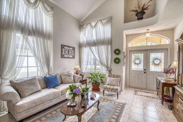 foyer featuring high vaulted ceiling, light tile patterned flooring, french doors, and a textured ceiling