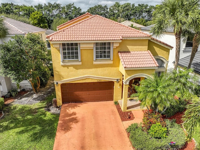 mediterranean / spanish-style home with stucco siding, a tiled roof, an attached garage, and driveway