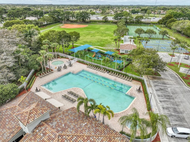 community pool with a patio, fence, and a hot tub