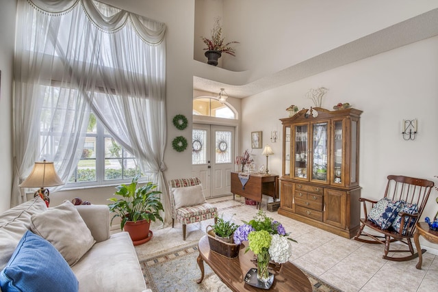 tiled living room with french doors and a towering ceiling