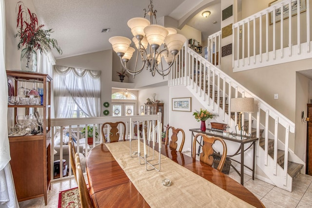 tiled dining room with stairway, visible vents, high vaulted ceiling, an inviting chandelier, and a textured ceiling